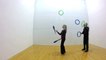 Woman Bounces Rings Off Wall While Performing Pass Juggling Trick With Man
