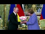 Vladimir Putin gives Angela Merkel flowers as they meet in the Kremlin