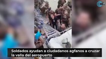 Soldados ayudan a ciudadanos agfanos a cruzar  la valla del aeropuerto