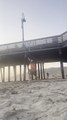 Guy Throws Football Over Pier While Another Guy Catches It After Running to Other Side