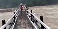 Ils traversent un pont piéton lors d'une crue