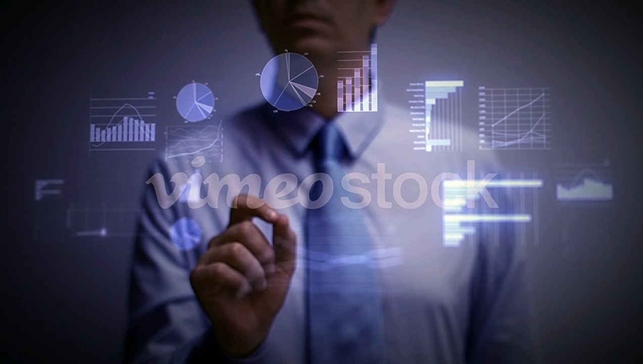 A_businessman_working_on_a_blue_holographic_interface,_touching_a_hologram_showing_a_visual_screen_with_computer_and_business_ic