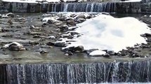 Água caindo de uma cachoeira com neve