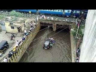 गुडघाभर पाण्यातून बंद पडलेली कार बाहेर काढण्याचे प्रयत्न