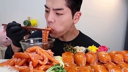 Handsome guy eating Salmons dipped in soy sauce and another sauce