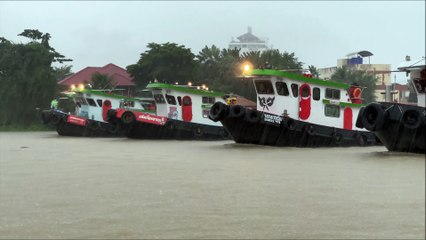 5 Tugboats pulling a huge barge during heavy rain in Thailand