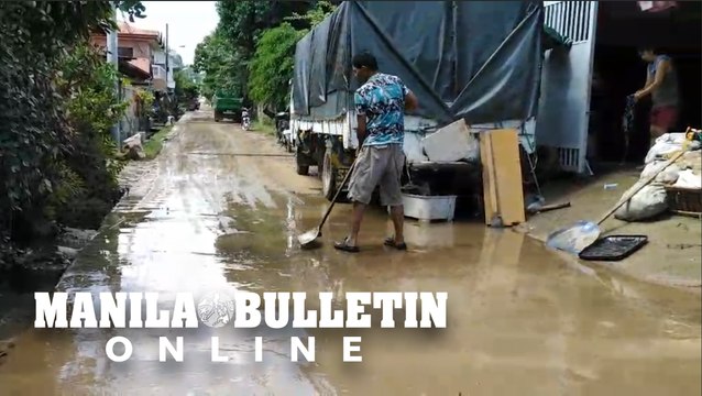 Residents clear mud from their houses following a flood in Davao City