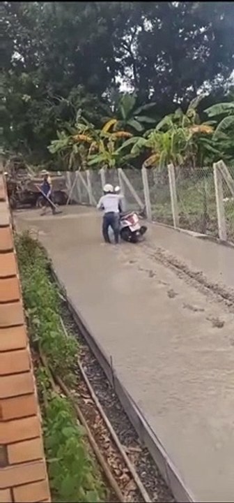 Il marche sur du béton frais sous les yeux des ouvriers