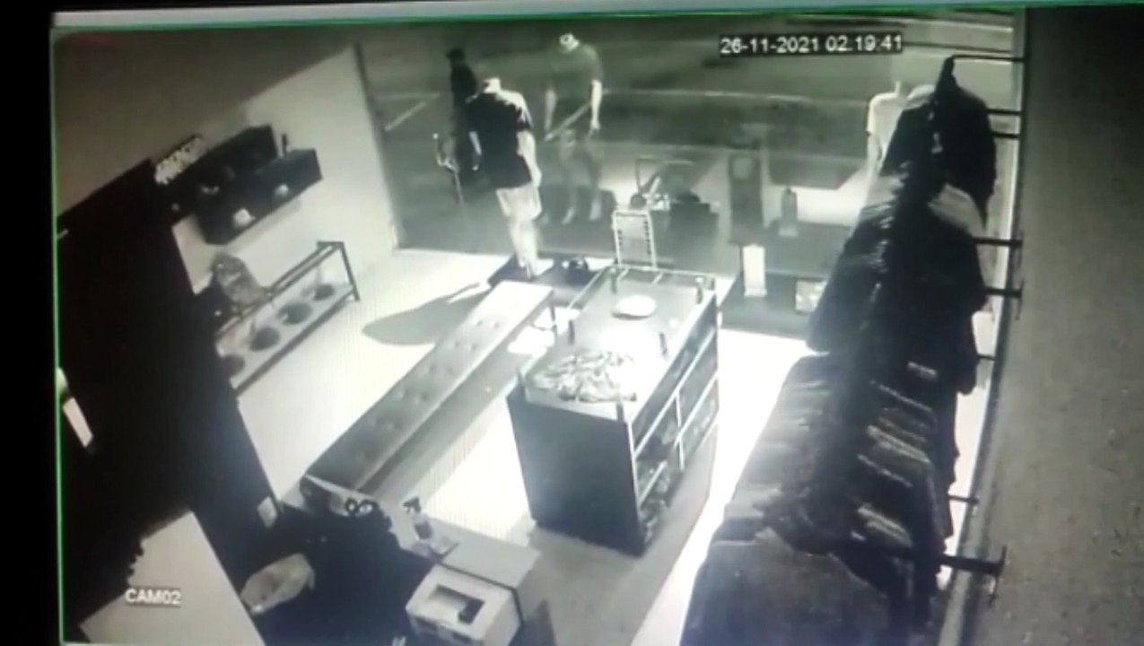Câmeras de segurança mostram bandidos armados estourando a porta da loja "na bicuda"