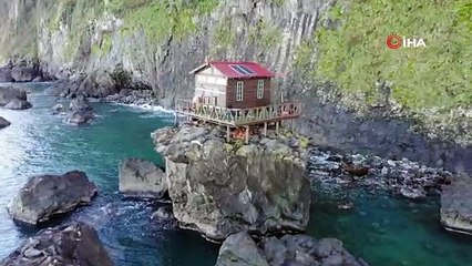 Deniz kıyısındaki kayanın üzerine yapılan baraka dikkat çekiyor