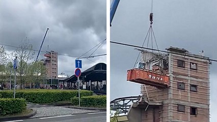 Une pelleteuse dans un conteneur perché en hauteur avec une grue