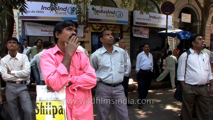 People look at a large screen displaying India's benchmark share index