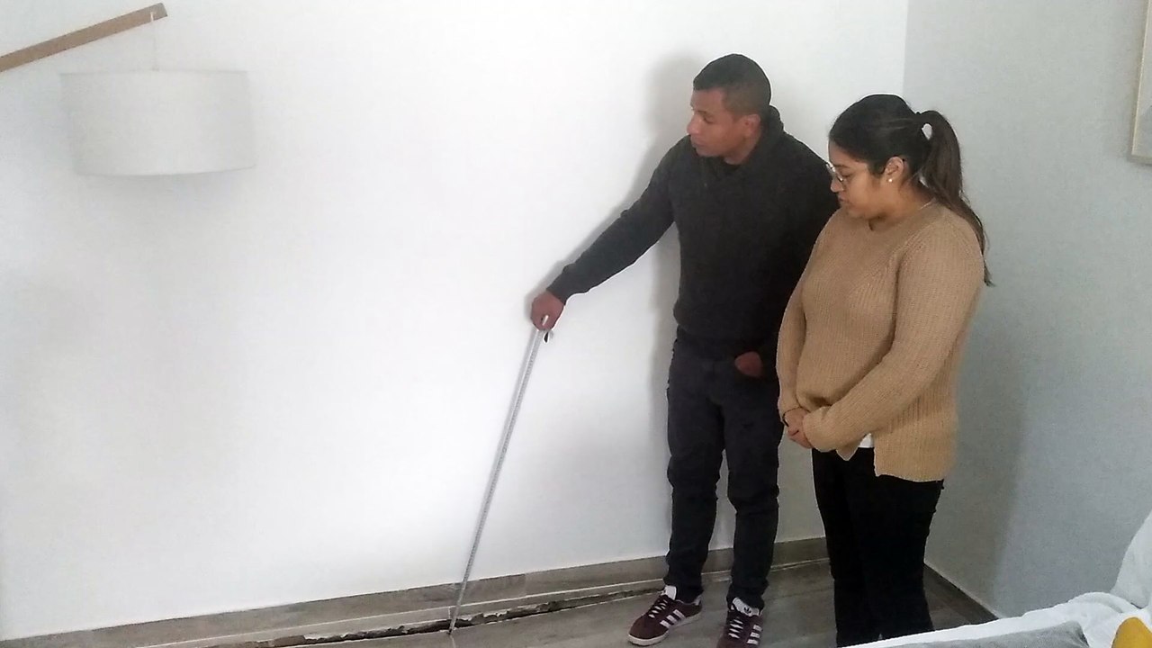 David y María, en el salón de su casa se Los Ramos, mostrando el hundimiento del suelo a causa de las filtraciones de una casa okupa.