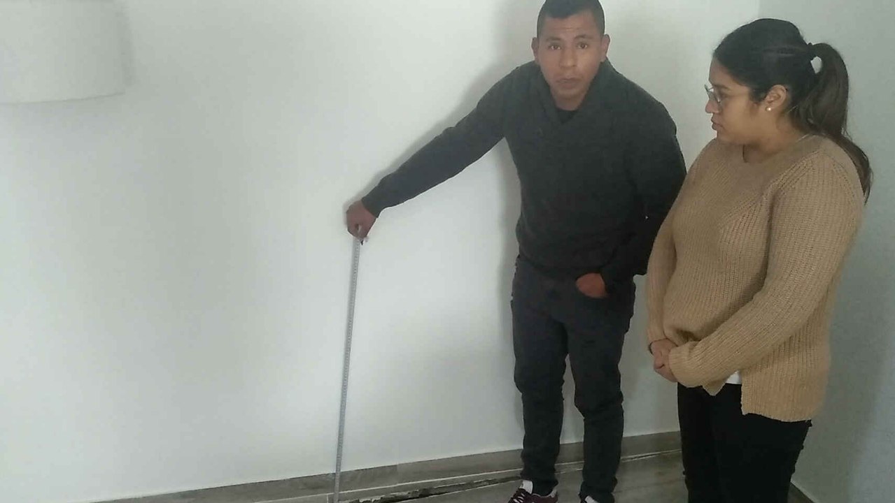 David y María, en el salón de su casa se Los Ramos, mostrando el hundimiento del suelo a causa de las filtraciones de una casa okupa.