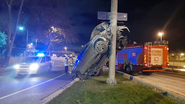Otomobil yön tabelası direğine asılı kaldı