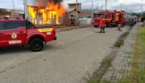 Homem se ajoelha em frente à própria casa em chamas