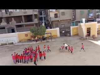 معلم بمدرسة ابتدائي يدفع كرسي متحرك لطالب ليشارك زملائه في سباق