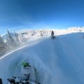 Two Guys Ride Their Snowmobiles Downhill on Snowy Slopes at British Columbia