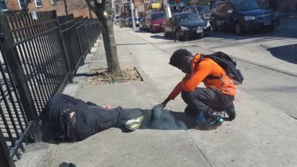 Ein Polizist fotografiert einen Jugendlichen, der den Fuß eines Obdachlosen hält und für ihn betet