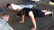 Ein Fitnessspezialist fordert einen Soldaten zu einem Liegestütz-Wettbewerb heraus