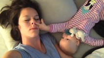 Cette femme essaye de faire une sieste avec son bébé. Mais il n'a pas l'air d'avoir très envie