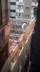 Un ouvrier travaille dangereusement sur le rebord d'une façade en démolition