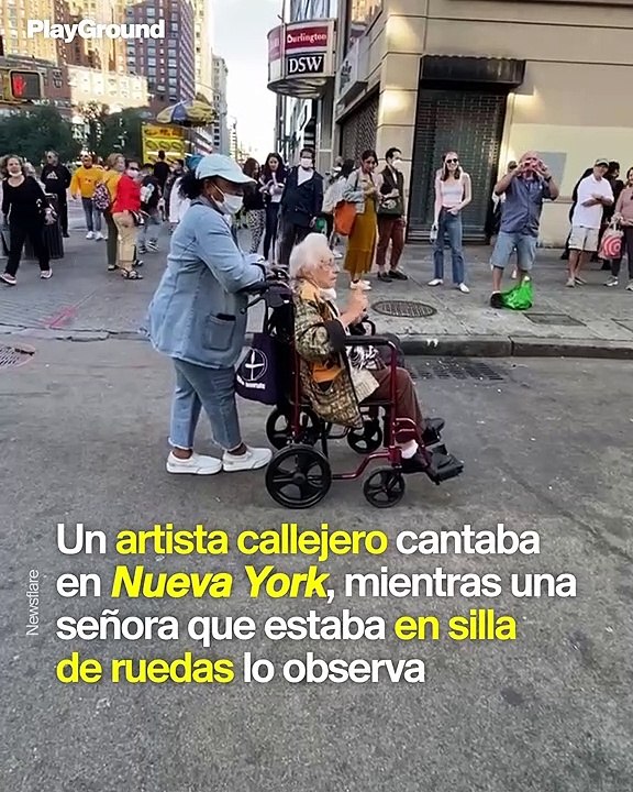 Una mujer se levanta de su silla de ruedas para bailar con un artista callejero