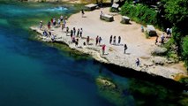 People standing on the bank of river Neretva and taking pictures of Old Bridge in Mostar