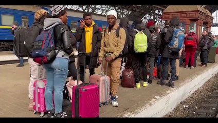 Ukrainiens et étrangers attendent un train à Lviv pour la Pologne