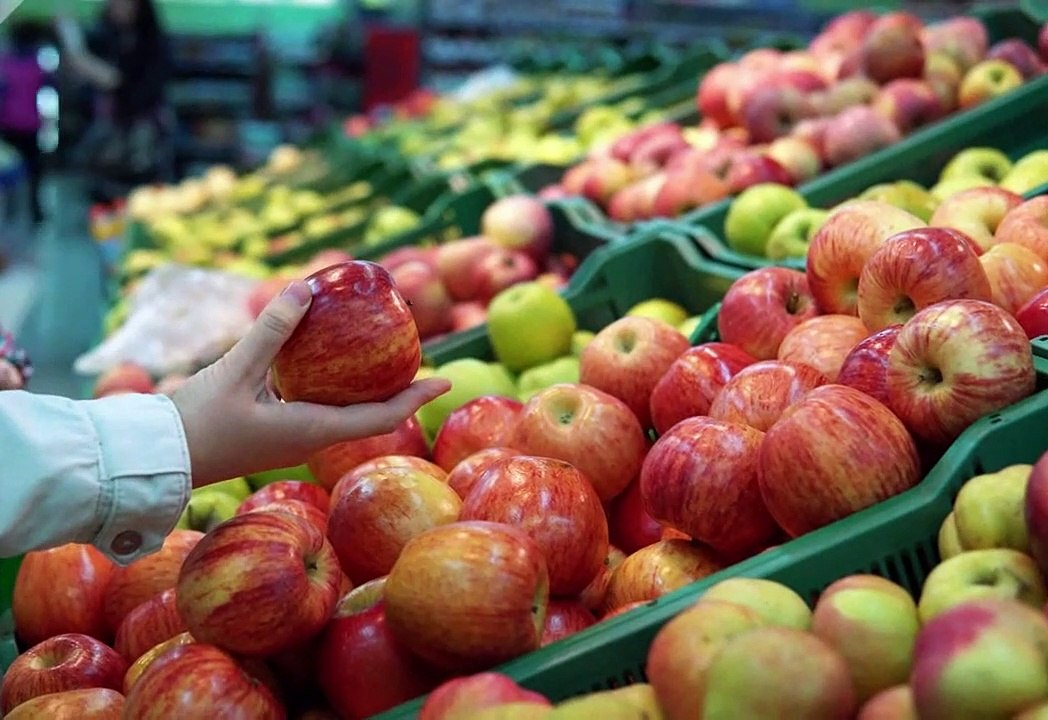 Checking red apple quality during buying in fruit shop