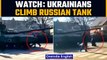 Ukrainians climb on top of Russian tanks in an effort to stop Russian military convoy |Oneindia News