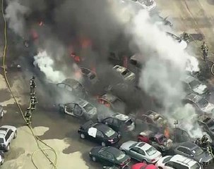 Dozens of cars burn as fire sweeps through a parking lot