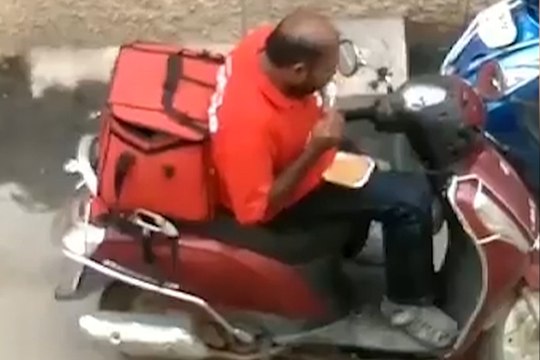 Cheeky delivery driver caught red-handed as he eats customer's food before resealing the box