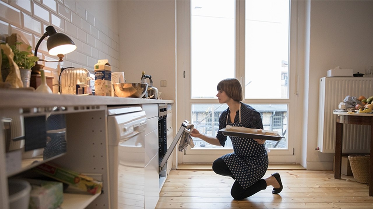 Frau backt einen Kuchen, plötzlich brennen Geldscheine mit