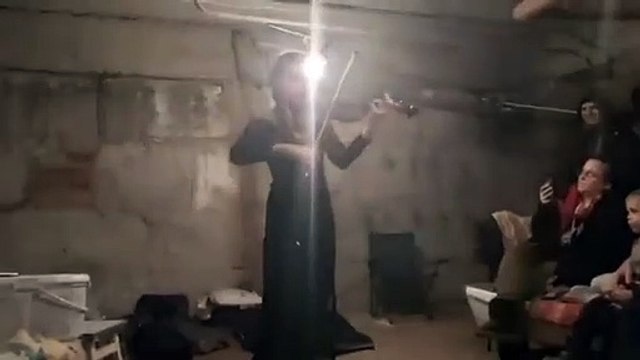 Une violoniste joue du violon dans les sous sols de bunker en Ukraine
