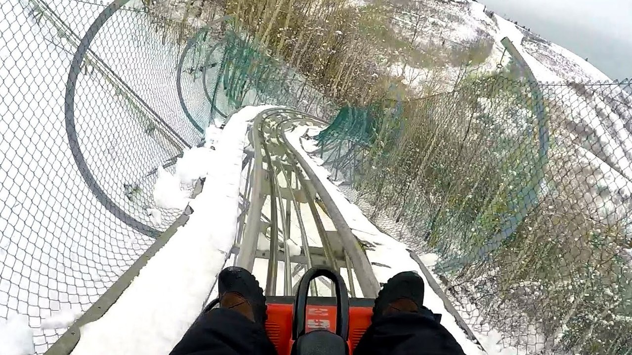 Il descend des montagnes russes enneigées sur une luge
