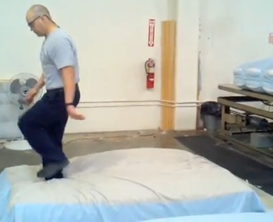 Le métier de cet homme est de sauter sur les matelas