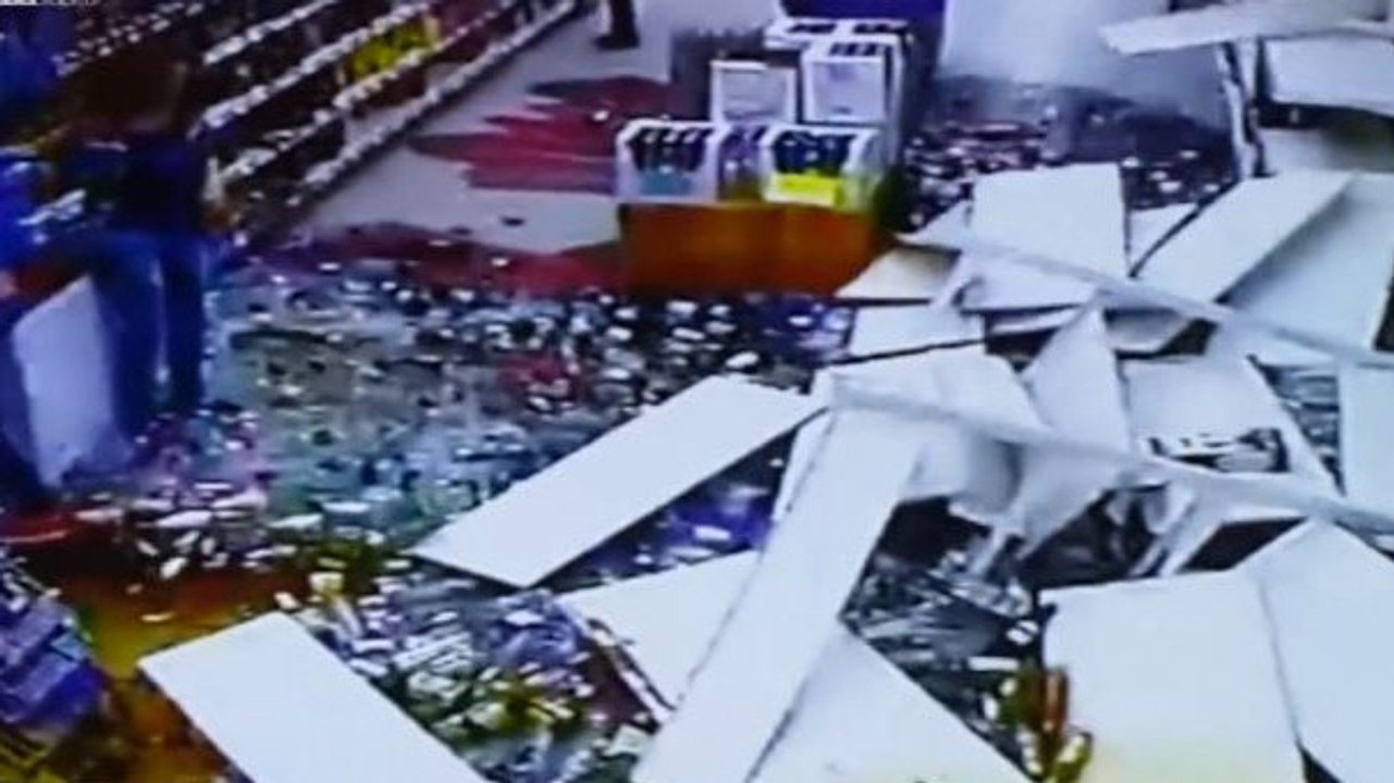 Un rayon rempli de bouteilles d'alcool tombe devant deux clientes et un employé