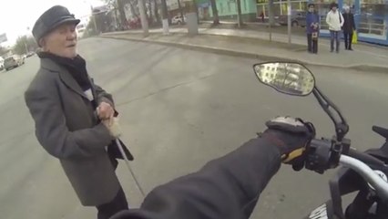 Ce motard aide une personne âgée à traverser la route sans descendre de sa moto