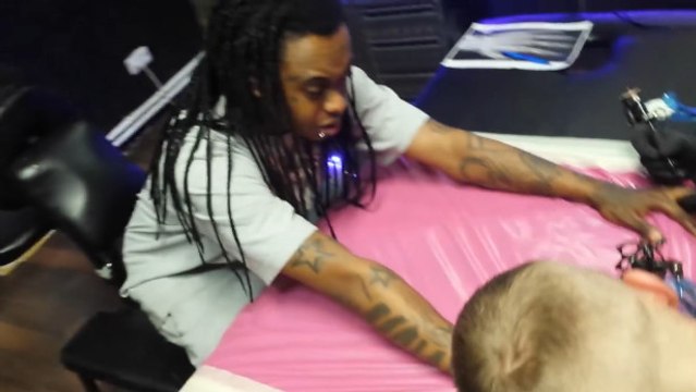 Cet homme se fait tatouer ses deux mains en même temps par deux tatoueurs différents