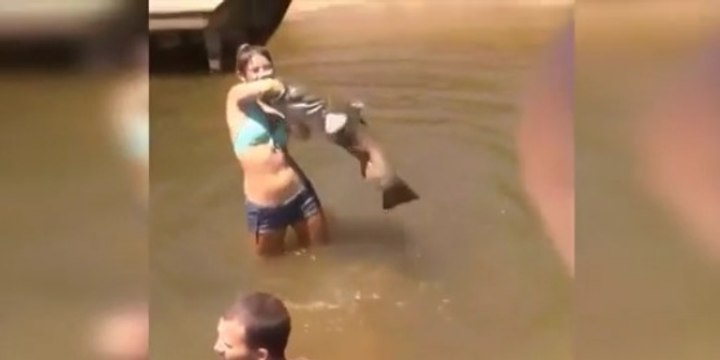 Une jeune femme attrape un poisson géant à mains nues