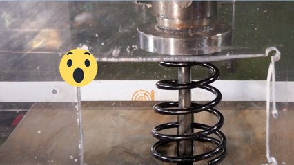 Un amortisseur de voiture se fait broyer par une presse hydraulique
