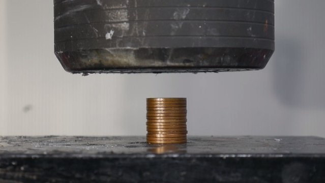 Il tente d'écraser des pièces de monnaie avec une presse hydraulique