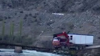 Une énorme camion tente de traverser un petit pont en bois