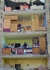 Homem recolhe pertences em prédio destruído pelos bombardeamentos em Kyiv