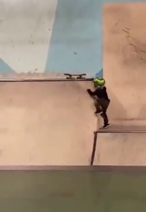 Un tout petit garçon tente de skater depuis une grande rampe