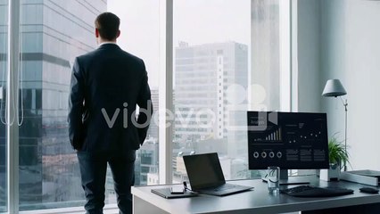 The cryptocurrency miner standins in his office and monitors stock exchange activity using infographics