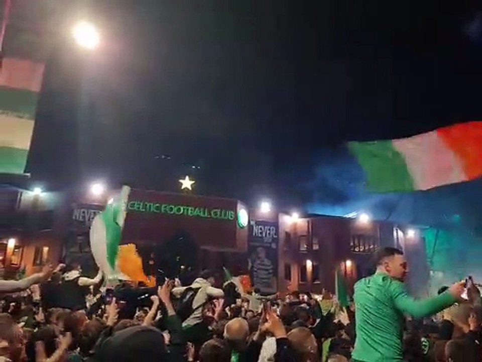 Celtic fans sing outside Celtic Park as they await the team