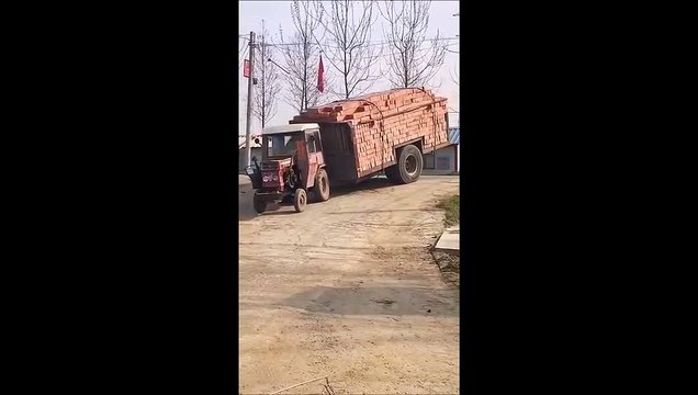 Un tout petit tracteur tire une énorme remorque