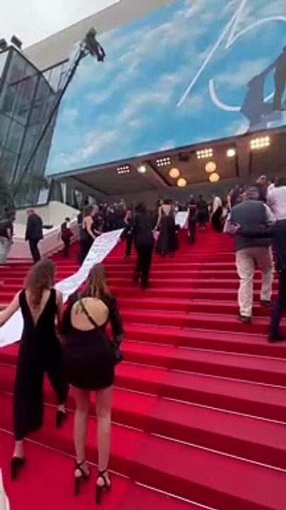 Une immense banderole avec le nom de victimes de féminicides en France déployée sur le tapis rouge à Cannes par des membres d'un collectif féministe